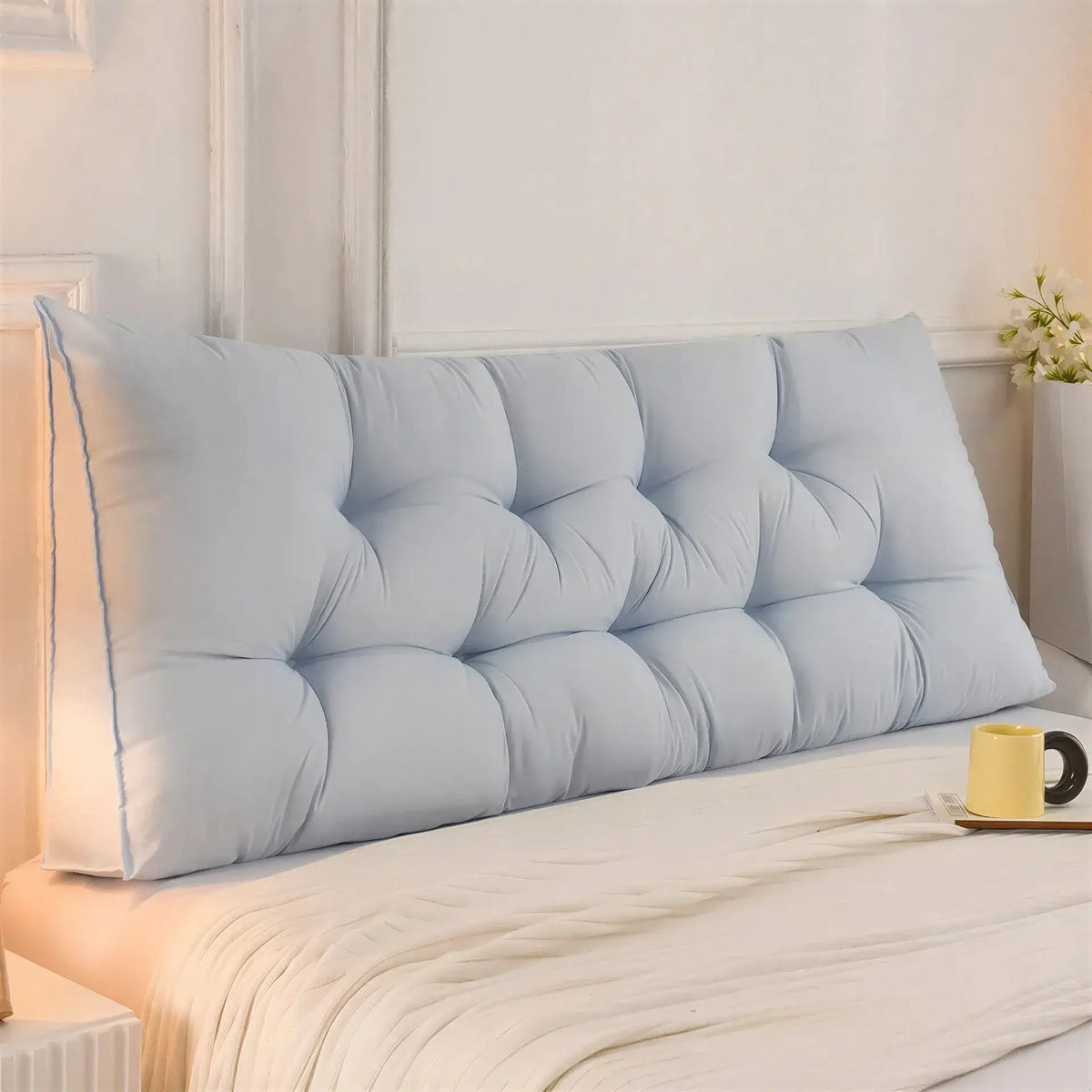 Zora triangular wedge headboard cushion on bed, providing comfortable support for bed and sofa use, in a neutral fabric.